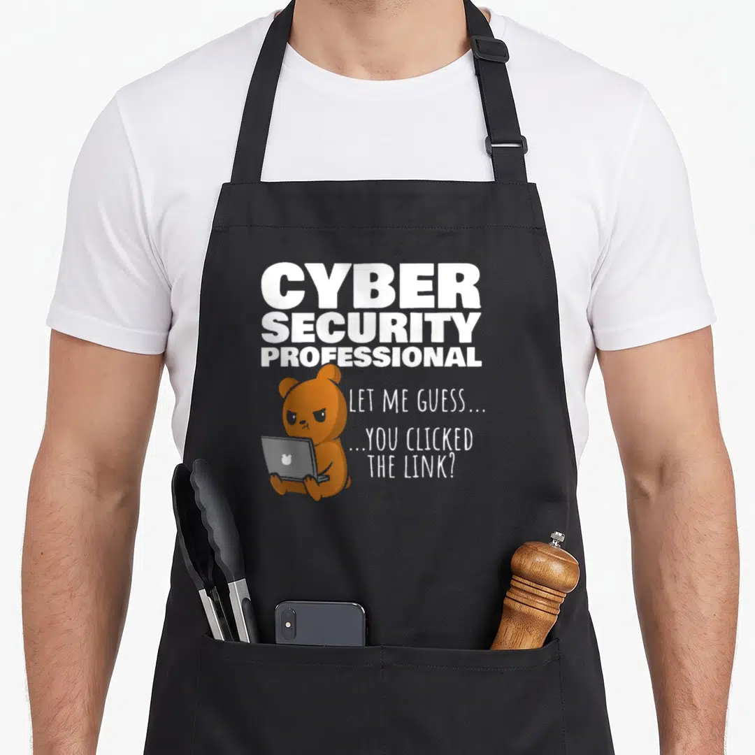 Clicked cybersecurity wife apron - Brown bear holding grey laptop under white CYBER SECURITY PROFESSIONAL text — shown on a black cotton canvas apron against a white background