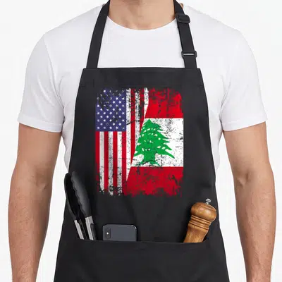 Lebanon american flag apron - Distressed merged US and Lebanon flags with red white blue green and a green cedar tree — shown on a black cotton canvas apron against a white background