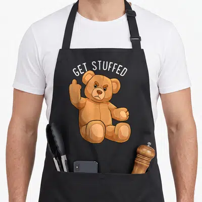 Stuffed teddy bear apron - Brown cartoon bear flipping finger under white arched text GET STUFFED — shown on a black cotton canvas apron against a white background