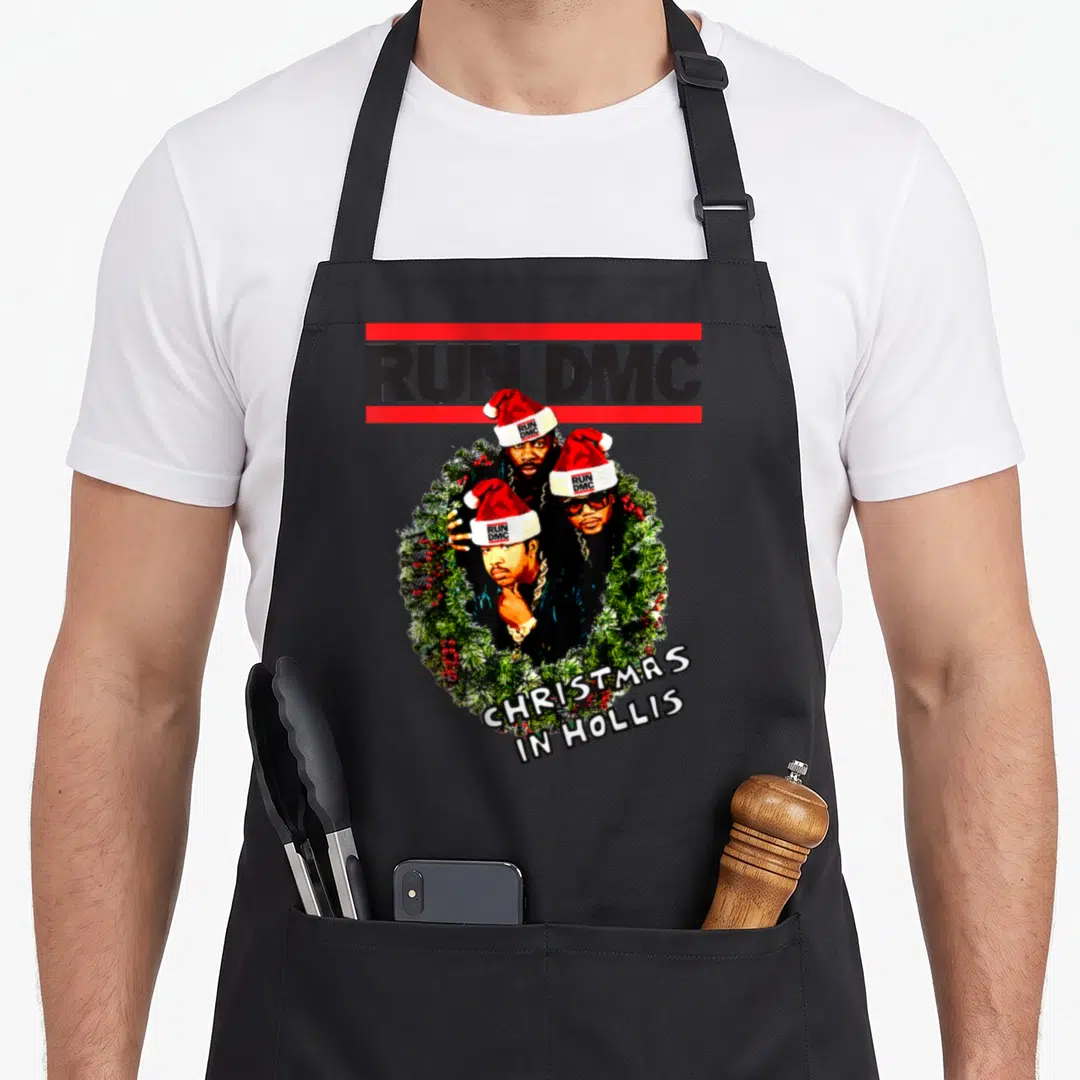 Run christmas apron - Three men in Santa hats inside a wreath with RUN DMC and CHRISTMAS IN HOLLIS text — shown on a black cotton canvas apron against a white background