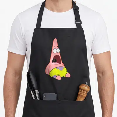 Squarepant patrick apron - Pink cartoon starfish wearing yellow shorts with purple flowers centered on gray background — shown on a black cotton canvas apron against a white background