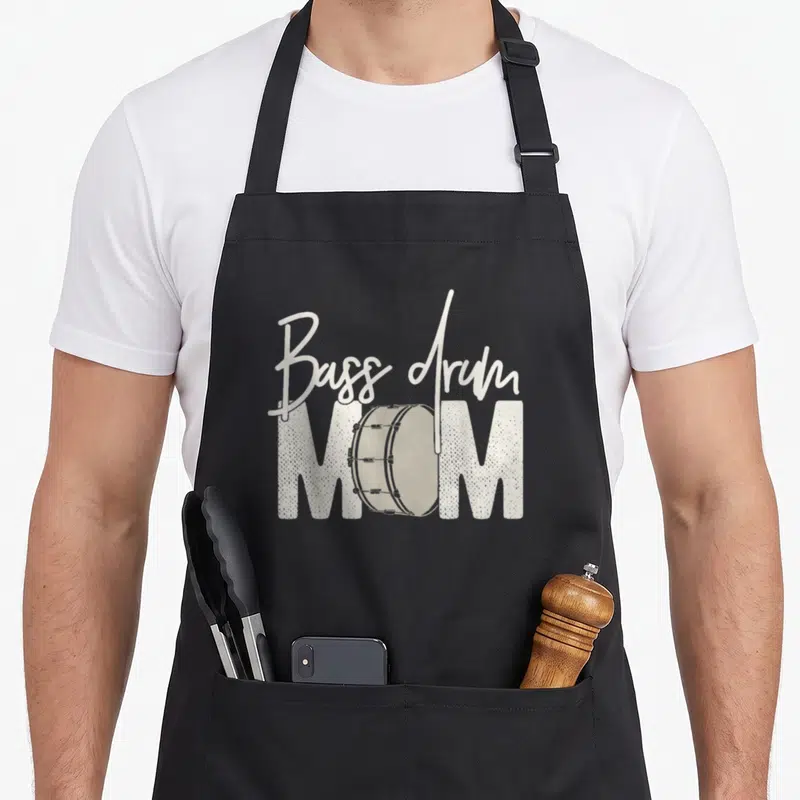 Bass mother's day aprons - Bass drum MOM text with grey drum illustration replacing the letter O — shown on a black cotton canvas apron against a white background