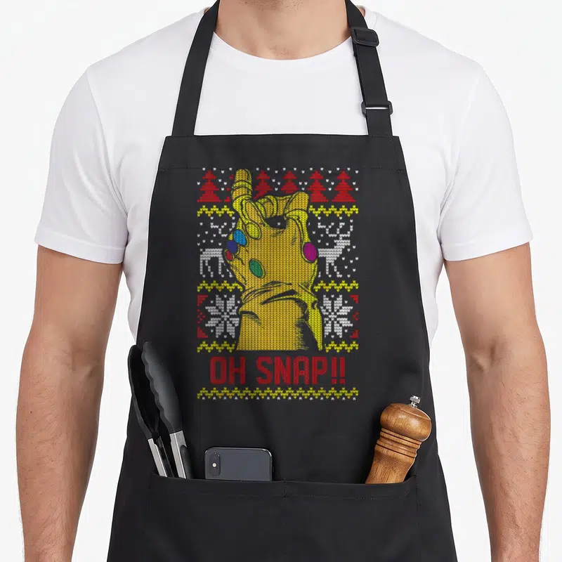 Snap ugly christmas sweater apron - Knitted yellow gauntlet with OH SNAP text and red white patterned stripes — shown on a black cotton canvas apron against a white background