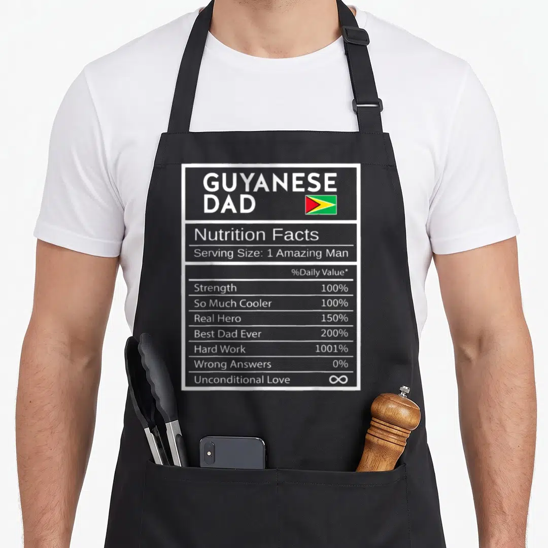 Guyanese nutrition pride apron - Grey nutrition facts label printed with GUYANESE DAD text and small Guyana flag — shown on a black cotton canvas apron against a white background