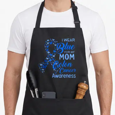 Blue i love tribute apron - Blue butterfly awareness ribbon next to I Wear Blue For My Mom Colon Cancer Awareness text — shown on a black cotton canvas apron against a white background