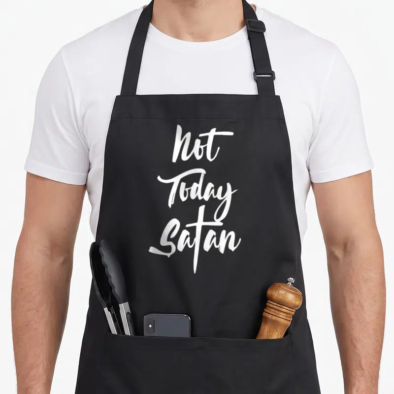 Today satan christian apron - White script text reading Not Today Satan stacked vertically on black fabric — shown on a black cotton canvas apron against a white background