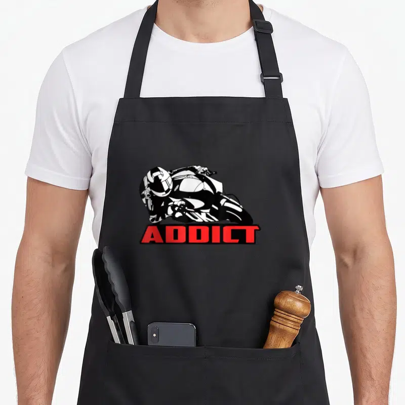 Addict motorcycle apron - Black and white line art of a motorcyclist leaning left with red ADDICT text in a box below — shown on a black cotton canvas apron against a white background