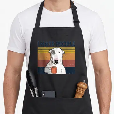 Hate bull terrier apron - I HATE PEOPLE text above a white dog holding an orange mug on blue, orange, and yellow stripes — shown on a black cotton canvas apron against a white background