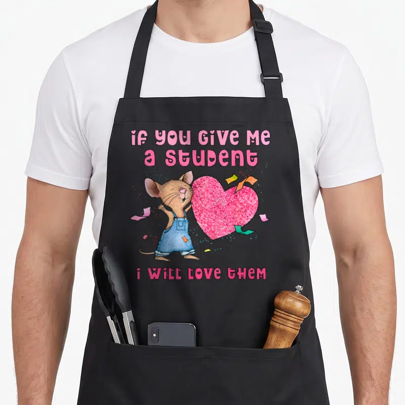 Mouse student aprons - Cartoon mouse in blue overalls holding pink heart with confetti and text about loving students — shown on a black cotton canvas apron against a white background