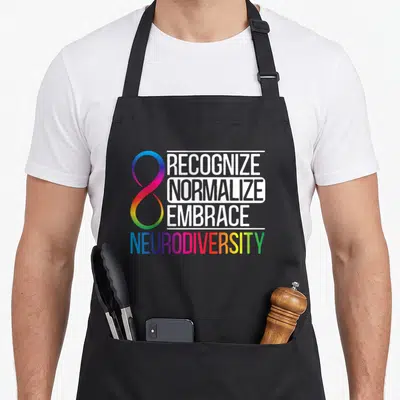 Recognize adhd awareness apron - Rainbow infinity symbol beside stacked white words RECOGNIZE NORMALIZE EMBRACE above — shown on a black cotton canvas apron against a white background