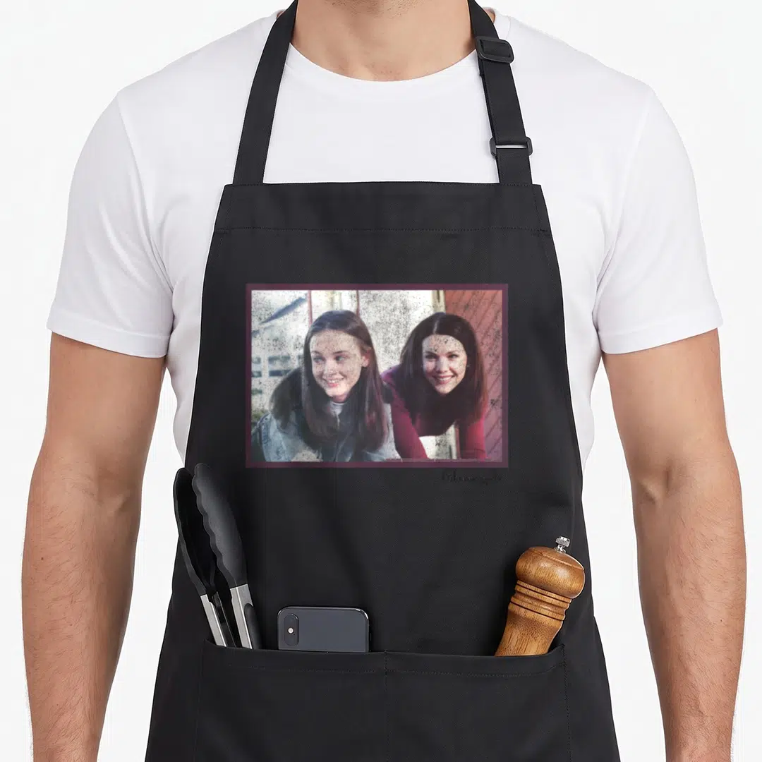 Rory gilmore girls apron - Photo of two women with Gilmore girls text below in grey brown red blue — shown on a black cotton canvas apron against a white background