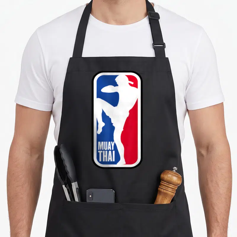 Fighter training apron - White fighter silhouette kicking over blue and red background with MUAY THAI text — shown on a black cotton canvas apron against a white background