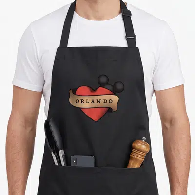 Orlando tampa florida apron - Red heart with black mouse ears and tan ribbon reading ORLANDO — shown on a black cotton canvas apron against a white background