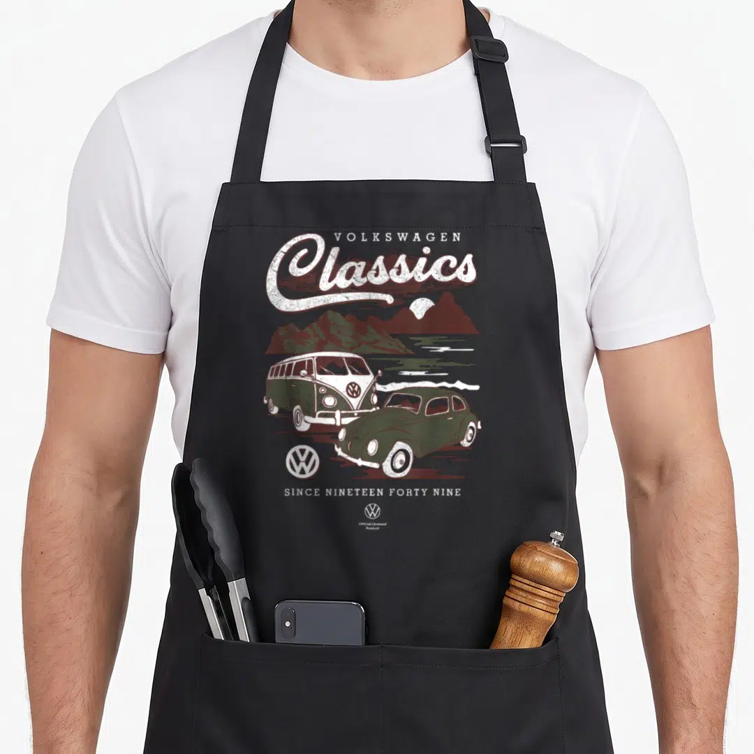 Campervan car iconic apron - Retro VW bus and beetle illustration with mountain landscape and Classics text — shown on a black cotton canvas apron against a white background