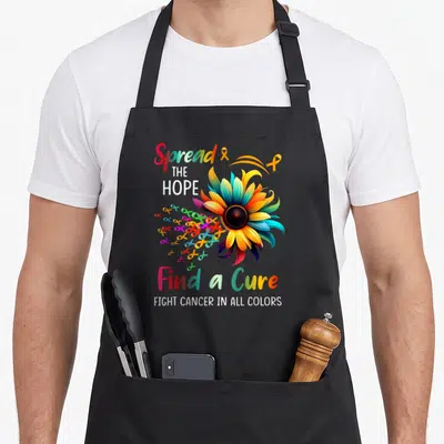 Fight sunflower apron - Multi-colored sunflower with ribbons and Spread the Hope Find a Cure text — shown on a black cotton canvas apron against a white background