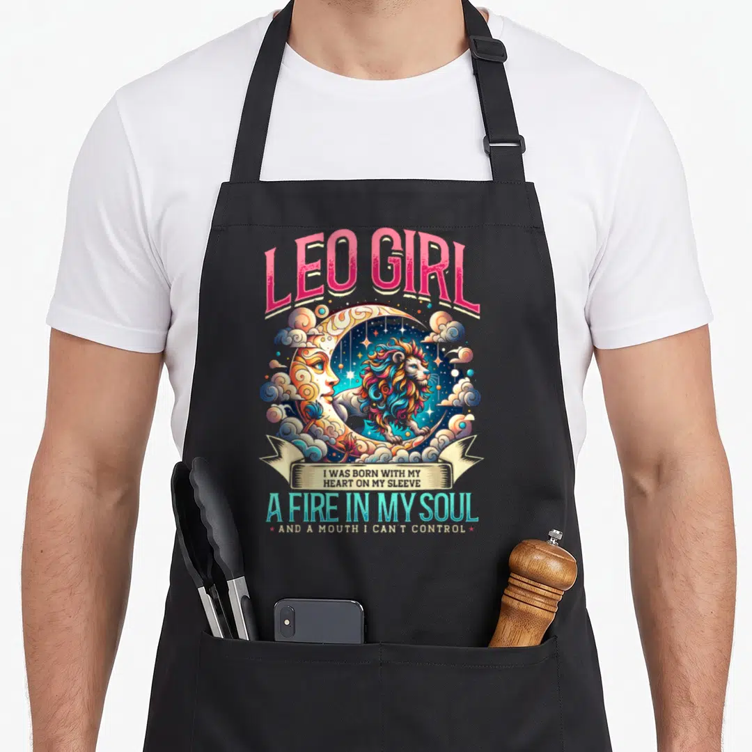 Moon zodiac aprons - Leo Girl lion on crescent moon with pink cyan yellow blue text and clouds — shown on a black cotton canvas apron against a white background