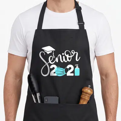 Senior paper apron - White Senior 2021 script with cap, blue mask, and sanitizer bottle — shown on a black cotton canvas apron against a white background
