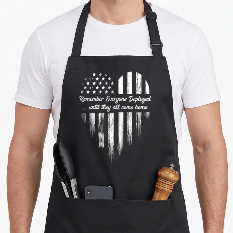 Friday american flag apron - White distressed heart shape with flag pattern and text Remember Everyone Deployed — shown on a black cotton canvas apron against a white background