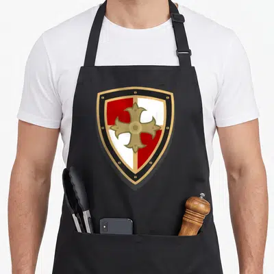 Knight renaissance apron - Minimalist shield with red white quadrants gold cross black border — shown on a black cotton canvas apron against a white background
