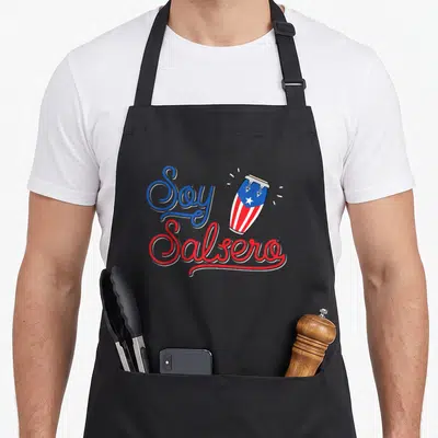 Salsero pride apron - Soy Salsero text and conga drum with Puerto Rican flag pattern in blue red white — shown on a black cotton canvas apron against a white background