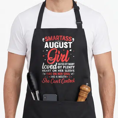 Smartass august girl apron - Red and white stacked text reading Smartass August Girl loved hated by many with small — shown on a black cotton canvas apron against a white background