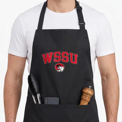 Arch ram apron - Red WSSU text arched over cartoon ram head logo in white and black — shown on a black cotton canvas apron against a white background