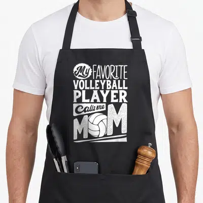 Volleyball mama mother's day aprons - White stacked text My Favorite Volleyball Player Calls me MOM with volleyball — shown on a black cotton canvas apron against a white background