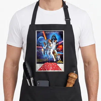 Thai new hope apron - Vintage Star Wars poster with misprinted English title and bold red Thai script over character — shown on a black cotton canvas apron against a white background