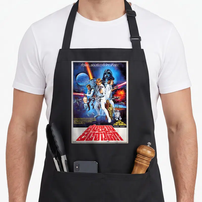 Thai new hope apron - Vintage Star Wars poster with misprinted English title and bold red Thai script over character — shown on a black cotton canvas apron against a white background