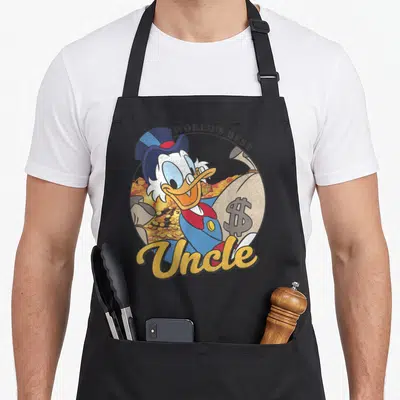 Ducktale uncle apron - Scrooge McDuck holding money bag with WORLD'S BEST and Uncle text in blue yellow gold — shown on a black cotton canvas apron against a white background