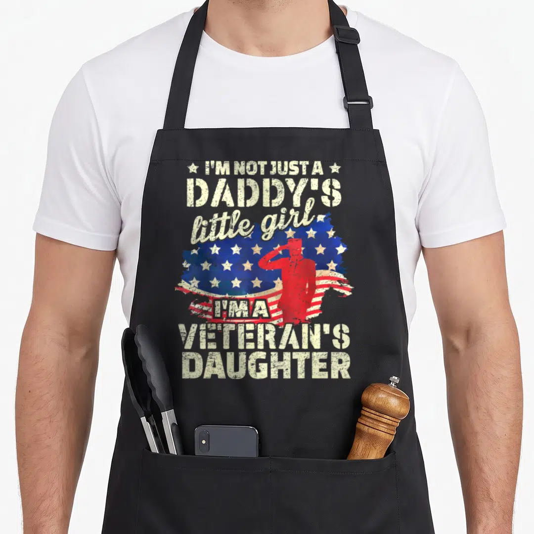 Proud female veteran apron - Red saluting soldier silhouette on distressed flag with beige text about being a veteran's — shown on a black cotton canvas apron against a white background
