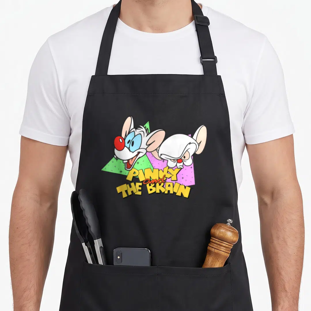 Pinky brain apron - Two cartoon mice above stacked yellow text PINKY and THE BRAIN with green and purple triangles — shown on a black cotton canvas apron against a white background