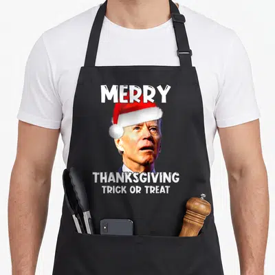 Joe santa aprons - Photo of Joe Biden in red Santa hat with white text Merry Thanksgiving Trick or Treat — shown on a black cotton canvas apron against a white background