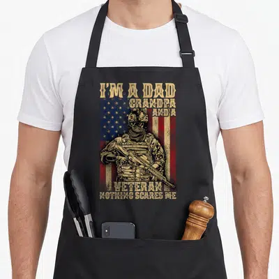 Flag grandpa 4th of july apron - Distressed soldier in front of USA flag with tan text I'm a Dad Grandpa and a Veteran — shown on a black cotton canvas apron against a white background