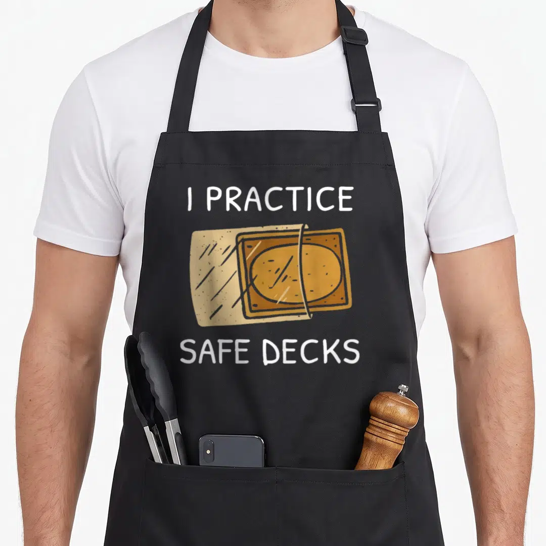Deckss safe apron - I Practice Safe Decks text with two overlapping tan and orange playing cards — shown on a black cotton canvas apron against a white background