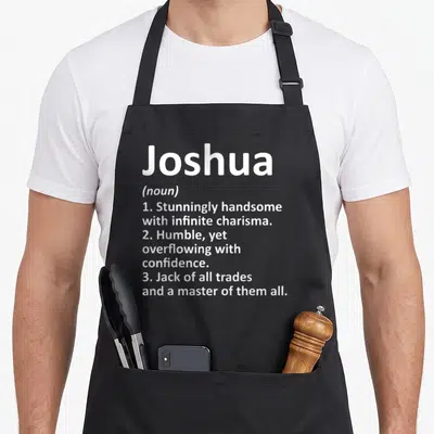 Meaning father day aprons - White text defining Joshua as handsome and a master of trades on gray background — shown on a black cotton canvas apron against a white background