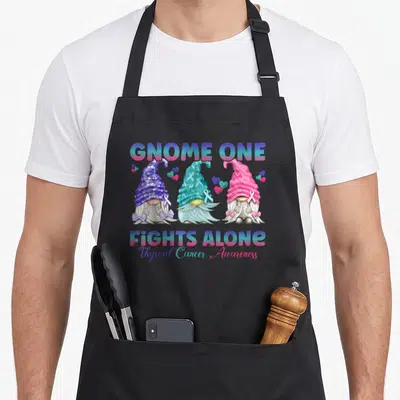 Alone thyroid apron - Three gnomes in blue pink purple and teal with Thyroid Cancer Awareness text — shown on a black cotton canvas apron against a white background