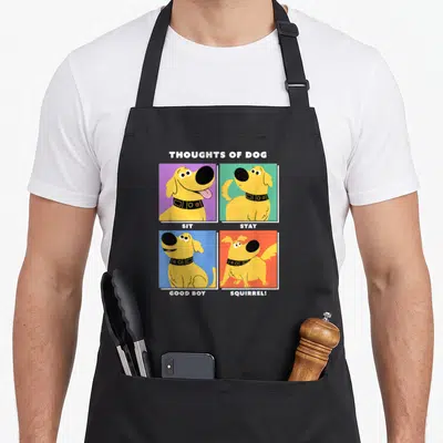 Dug dog apron - Yellow cartoon dog on purple green blue and orange squares with text Sit Stay Good Boy Squirrel — shown on a black cotton canvas apron against a white background