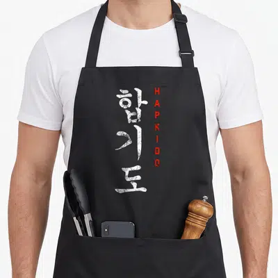 Hapkido korean apron - Vertical white Korean characters and red HAPKIDO text in distressed style — shown on a black cotton canvas apron against a white background