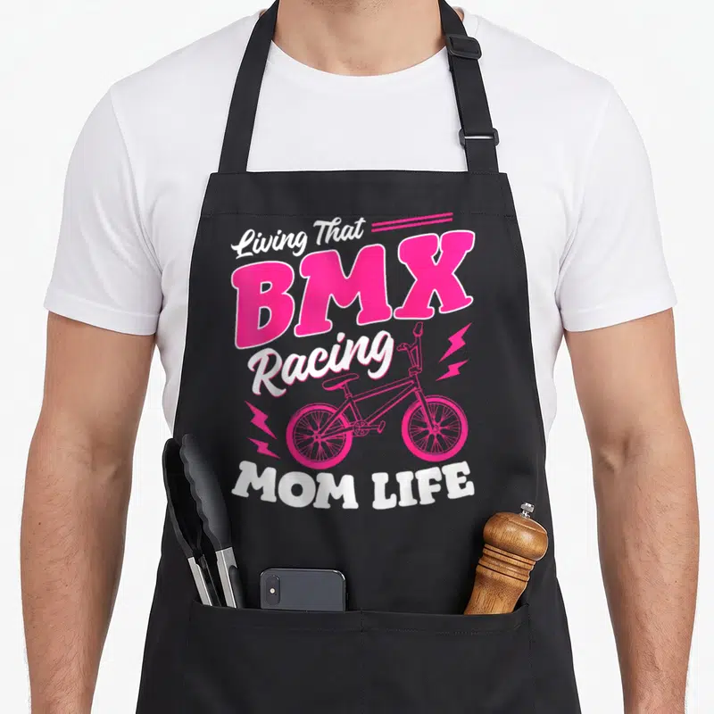 Bmx outdoor apron - Pink BMX bike and text Living That BMX Racing MOM LIFE on black bib — shown on a black cotton canvas apron against a white background