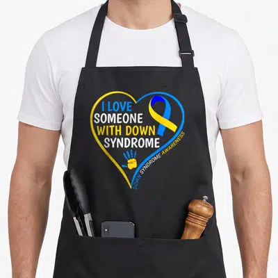 Someone down syndrome awareness apron - Blue yellow heart outline with I LOVE SOMEONE WITH DOWN SYNDROME text ribbon — shown on a black cotton canvas apron against a white background