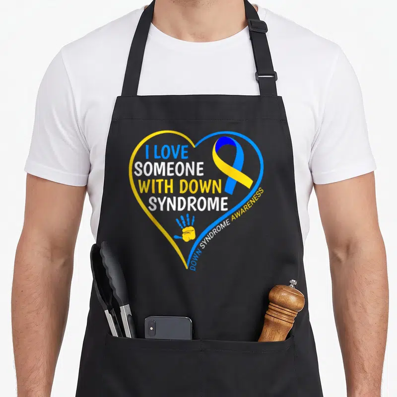 Someone down syndrome awareness apron - Blue yellow heart outline with I LOVE SOMEONE WITH DOWN SYNDROME text ribbon — shown on a black cotton canvas apron against a white background