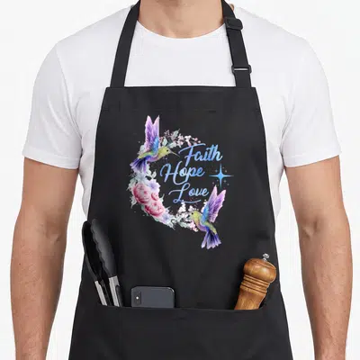 Hope bird apron - Two hummingbirds in purple blue pink and green watercolor framing Faith Hope Love text with a star — shown on a black cotton canvas apron against a white background