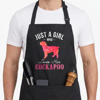 Cute dog cockapoo apron - Just A Girl Who Loves Her Cockapoo text with pink orange dog silhouette — shown on a black cotton canvas apron against a white background