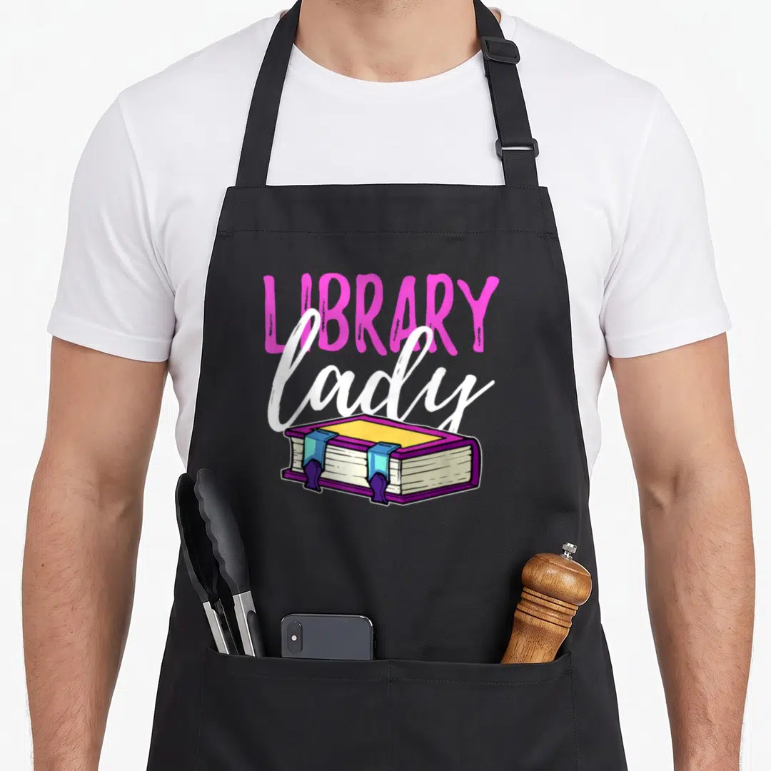 Librarian book squad apron - Pink LIBRARY text, white lady script, and purple closed book illustration — shown on a black cotton canvas apron against a white background