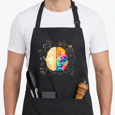 Colorful science apron - Split brain with chemistry formulas and art tools in watercolor style — shown on a black cotton canvas apron against a white background