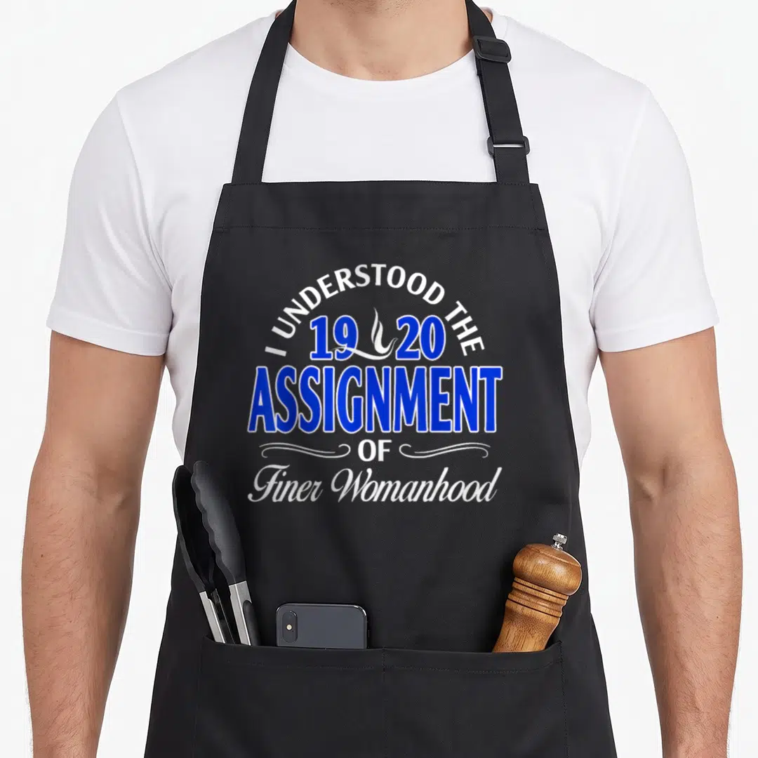 Phi sorority apron - Blue and white text reading I UNDERSTOOD THE 1920 ASSIGNMENT OF Finer Womanhood with a flame — shown on a black cotton canvas apron against a white background