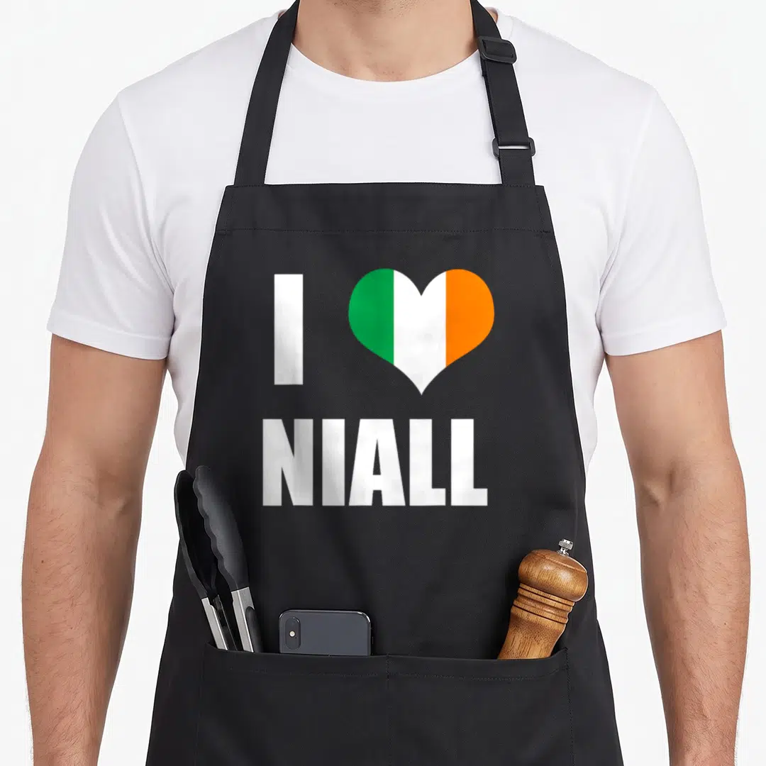 Niall ireland apron - I NIALL text with green white and orange vertical striped heart — shown on a black cotton canvas apron against a white background