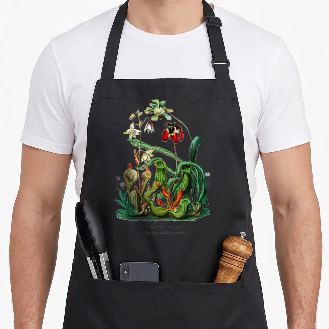Sarracenia plant apron - Realistic green and red pitcher plant cluster with flowers on black fabric — shown on a black cotton canvas apron against a white background