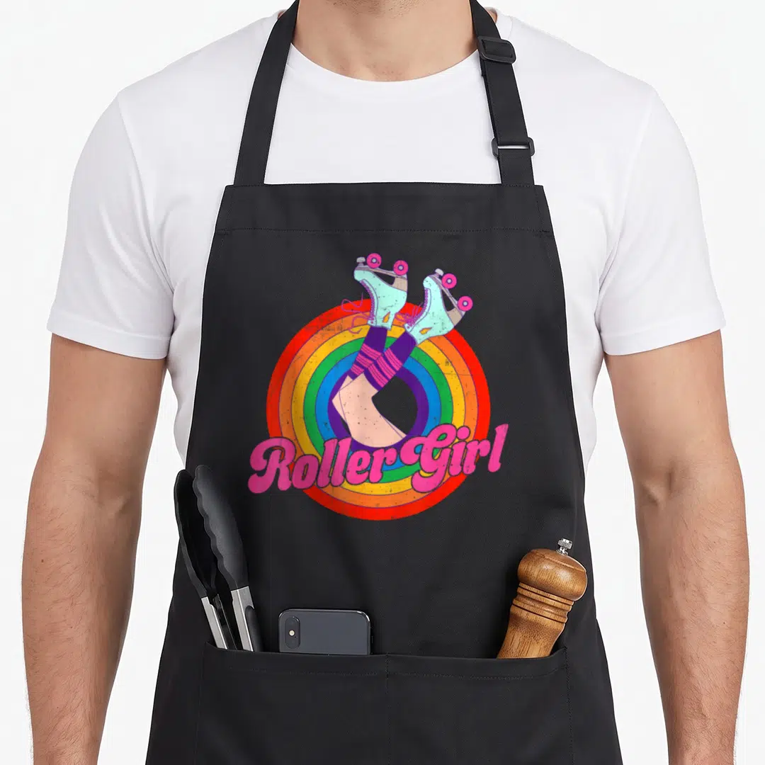 Skate 70s apron - Roller Girl text over rainbow circle with teal roller skates and striped socks — shown on a black cotton canvas apron against a white background